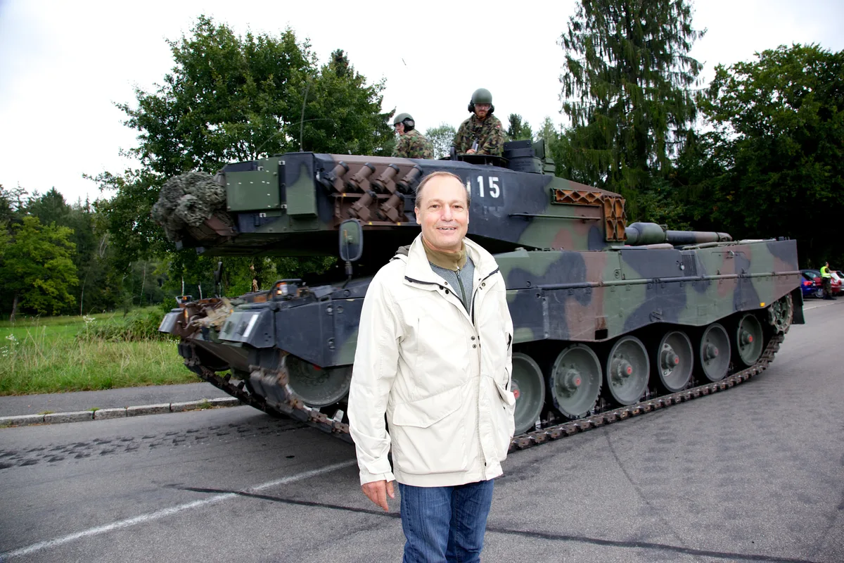 Jörg Kündig posiert vor einem Panzer.